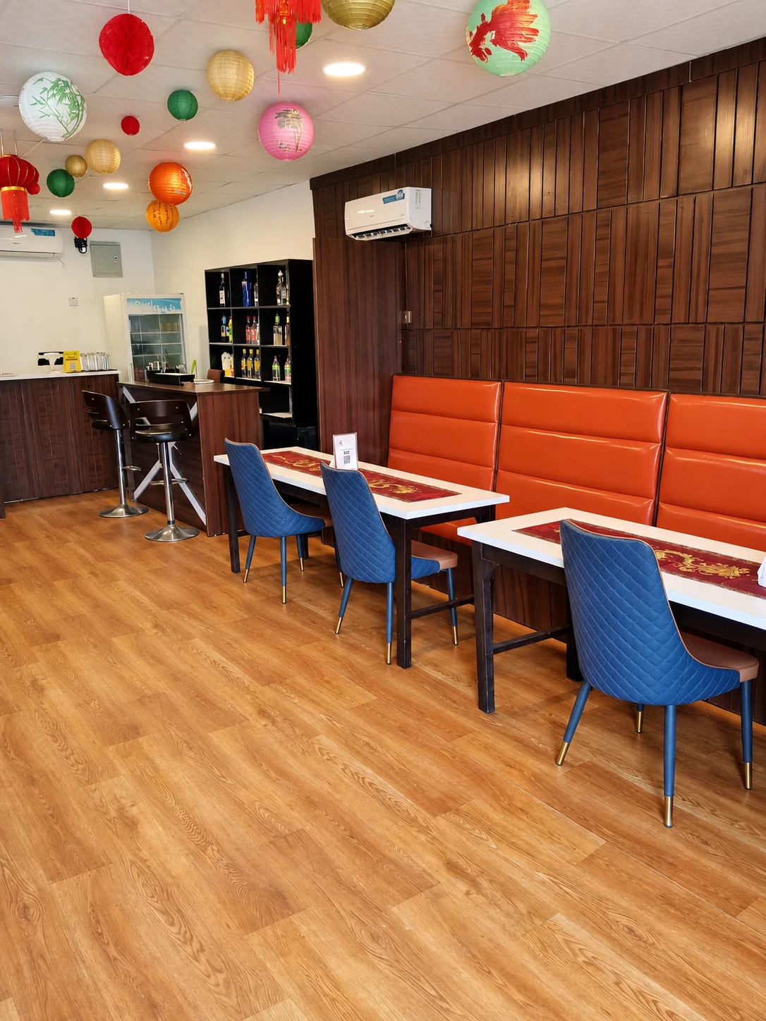 WokInn dining room with blue chairs, orange seating and colourful lanterns